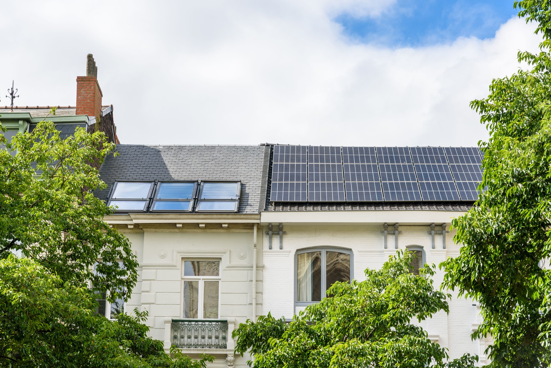 Solar panels for electricity generation on the roof of a town house on a partly cloudy summer day